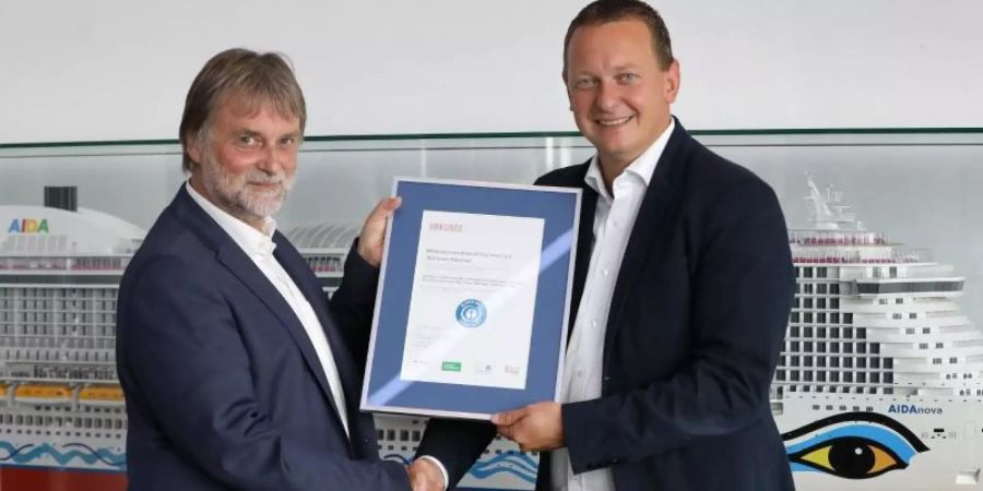 Ralf-Rainer Braun (l), Vorsitzender der Jury Umweltzeichen, überreicht Felix Eichhorn, Präsident von Aida Cruises, die Urkunde «Blauer Engel». Foto: Bernd Wüstneck