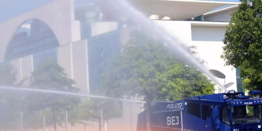 Bei Temperaturen um 30 Grad und extremer Trockenheit bewässert ein Wasserwerfer der Polizei die Grünanlagen vor dem Bundeskanzleramt. Foto: Wolfgang Kumm