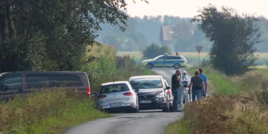 Mitarbeiter der Spurensicherung stehen auf einem Weg in der Nähe des Resthofs des Tatverdächtigen in Nordfriesland. Foto: Benjamin Nolte