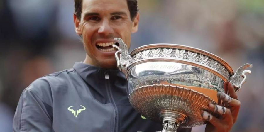 Rafael Nadal beisst nach seinem Sieg in die Trophäe. Foto: Christophe Ena/AP