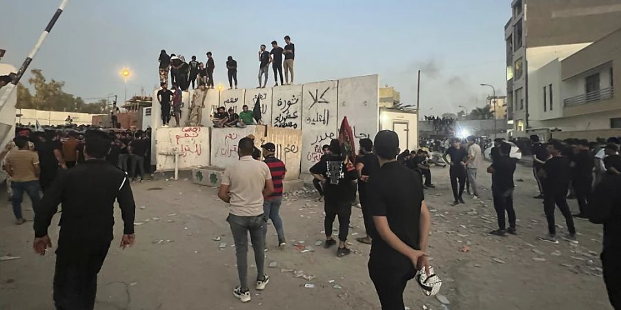 Demonstranten erklimmen eine Mauer an der schwedischen Botschaft. Foto: Ali Jabar/AP/dpa