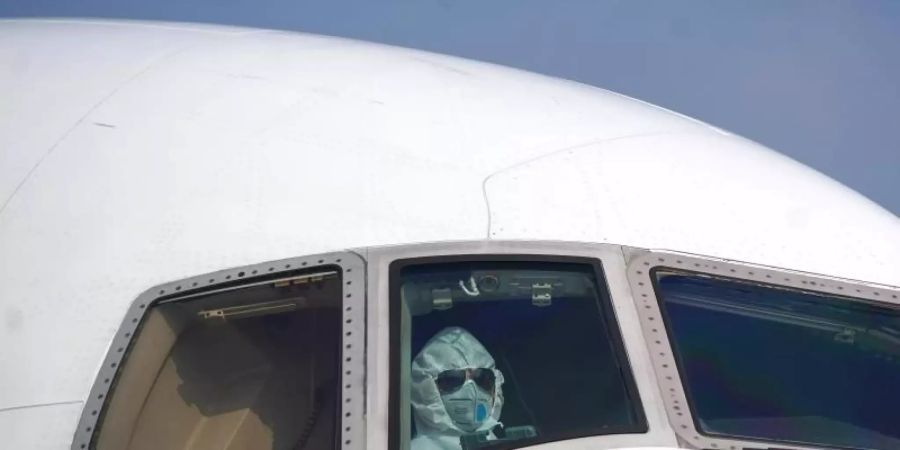 Ein Pilot sitzt mit Schutzanzug und Atemschutzmaske im Cockpit. Wie zuvor bereits Lufthansa und die niederländische KLM hat nun auch der Billigflieger Easyjet ein Sparprogramm aufgelegt, um der Krise zu begegnen. Foto: Cheng Min/XinHua/dpa