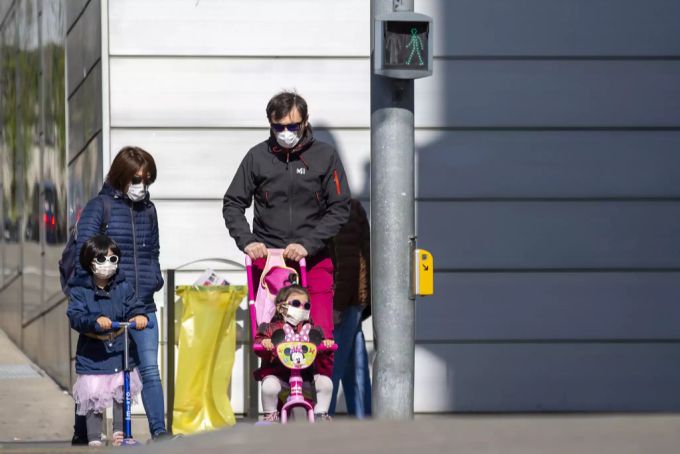 Eine vierköpfige Familie mit Schutzmasken wartet am Karfreitag in Genf auf grünes Licht. Laut Alain Berset könnte ein solches Bild in der Schweiz bald öfters zu sehen sein. Coronavirus Schweiz Alain Berset
