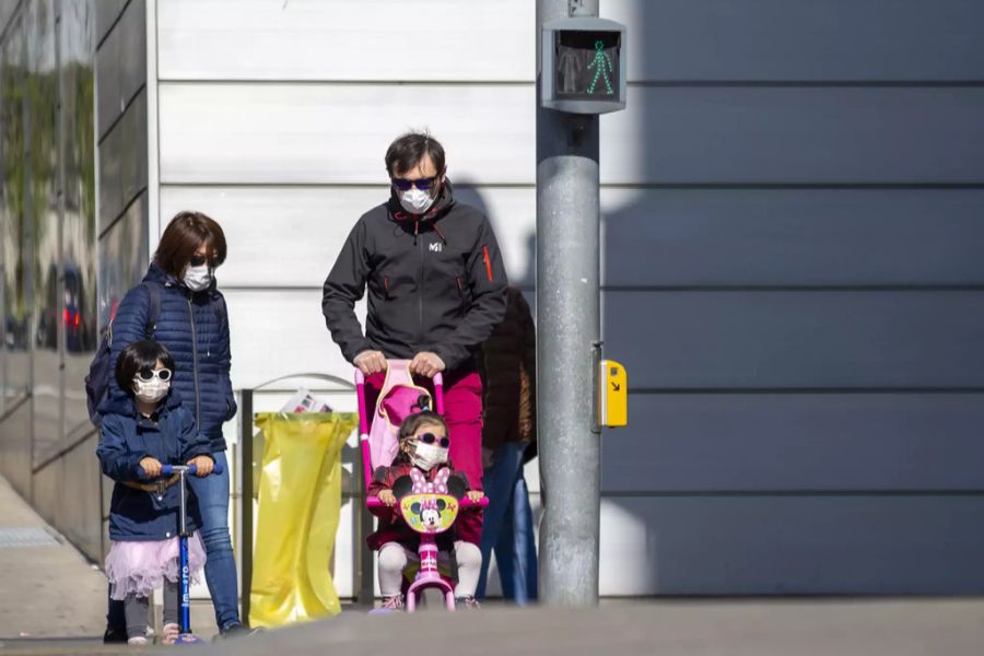 Eine vierköpfige Familie mit Schutzmasken wartet am Karfreitag in Genf auf grünes Licht. Laut Alain Berset könnte ein solches Bild in der Schweiz bald öfters zu sehen sein.