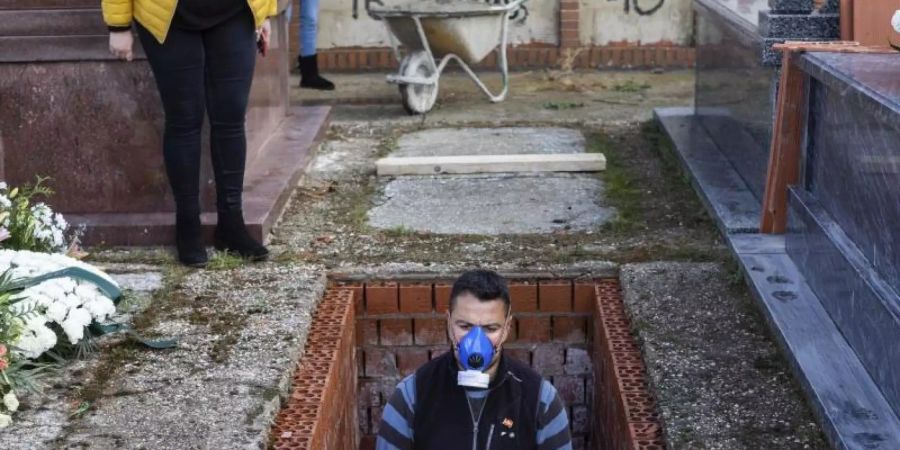 Ein Leichenbestatter in Spanien bereitet ein Grab vor während der Beerdigung einer 86-jährigen Frau mitten in der Corona-Krise. Foto: Bernat Armangue/AP/dpa