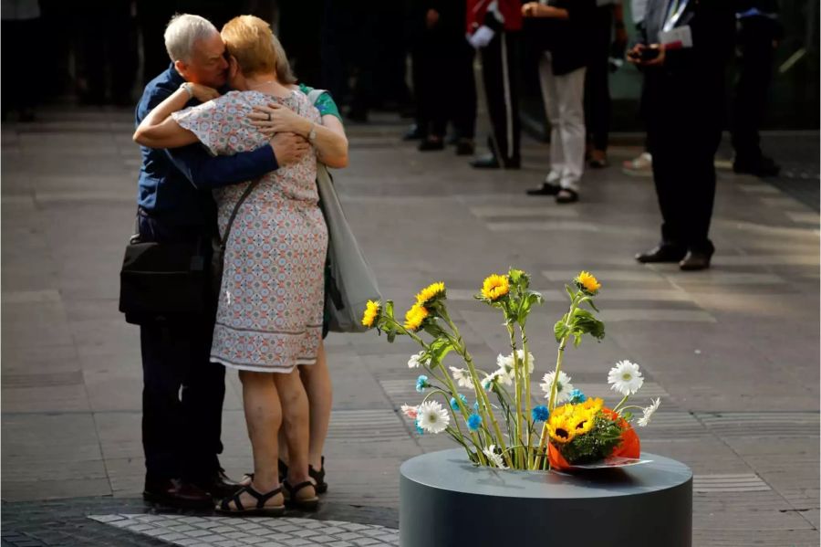 Angehöriger der Anschlagsopfer umarmen sich in Trauer, nachdem sie Blumen auf das Mosaik des katalanischen Künstlers Joan Miro abgelegt haben. Das Kunstwerk markiert den Punkt, an dem der Wagen des Terroristen auf Las Ramblas in Barcelona zum stehen kam.