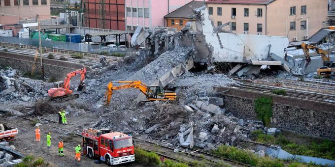 Feuerwehrleute entfernen Trümmer der teilweise eingestürzten Morandi-Autobahnbrücke. Feuerwehrleute entfernen Trümmer der teilweise eingestürzten Morandi-Autobahnbrücke.