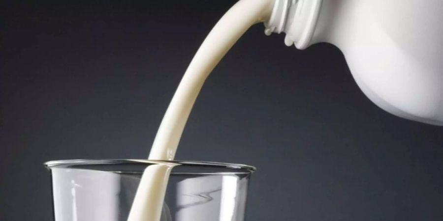 Milch wird aus einer Flasche in ein Glas eingeschenkt.