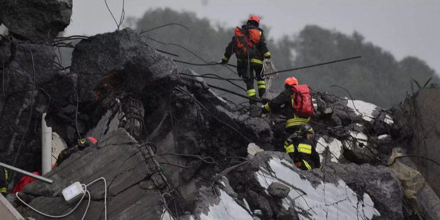 Rettungskräfte suchen in den Trümmern der eingestürzten Autobahnbrücke in Genua (IT) nach Todesopfern.