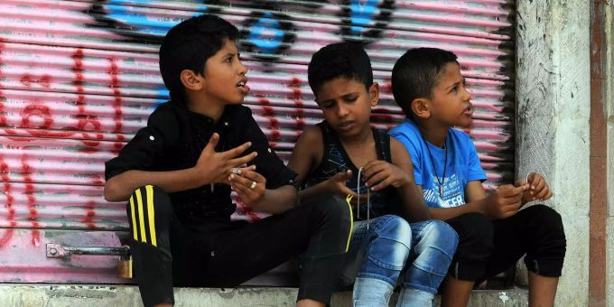 Drei Kinder sitzen vor einem geschlossenen Laden. Drei Kinder sitzen vor einem geschlossenen Laden.
