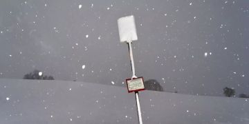 Ein mit Schnee bedecktes Schild an einer Bushaltestelle.