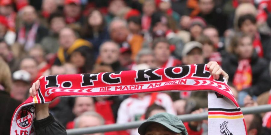 Ein Fan des 1. Fc Kölns hält einen Fanschal in die Luft.