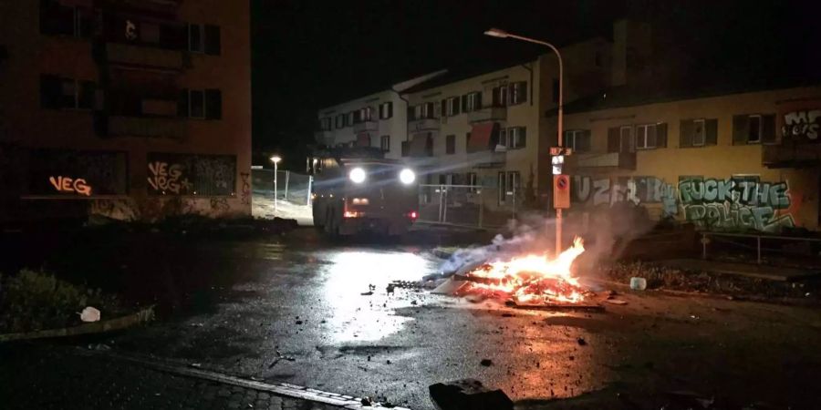 Randalierer errichten Barrikaden und stecken Container in Brand.