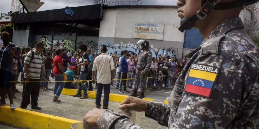 Ein Soldat beobachtet in einer Strasse in Caracas Demonstranten. Foto: Rayner Pena/Archiv