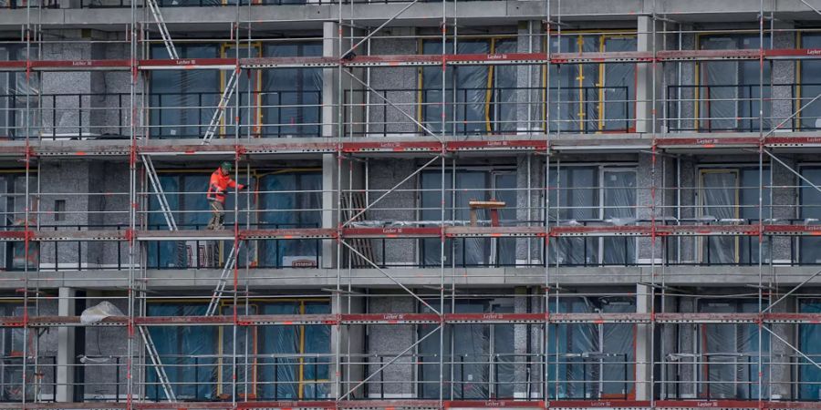 Gebäude in der Bauphase mit Gerüsten und einem Bauarbeiter darauf - Keystone