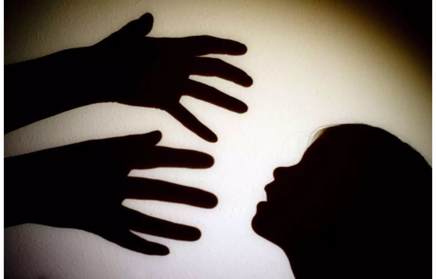 Schatten von Händen einer erwachsenen Person und Kopf eines Kindes - Keystone
