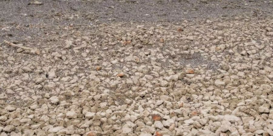 Steine und Sand, wo einst Wasser war, zeugen von der anhaltenden Trockenheit beim Lac des Brenets.