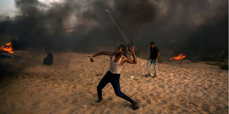 Ein palästinensischer Demonstrant wirft Steine bei Protesten im Gazastreifen.