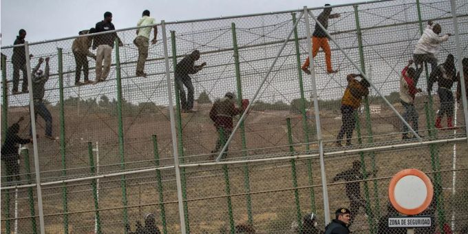 Migranten klettern über den Zaun an der Grenze zwischen Marokko und Melilla. Migranten klettern über den Zaun an der Grenze zwischen Marokko und Melilla.