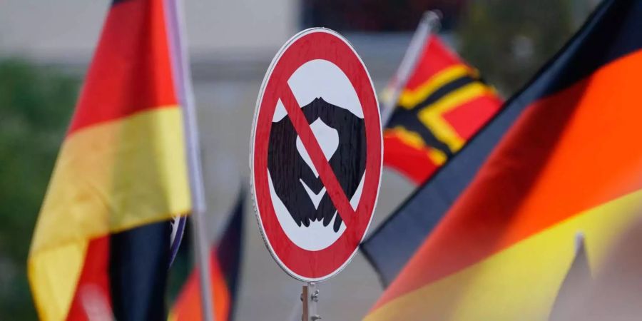 Ein Verbotsschild an einer Pegida-Demo zeigt die typische Geste der deutschen Bundeskanzlerin Angela Merkel.