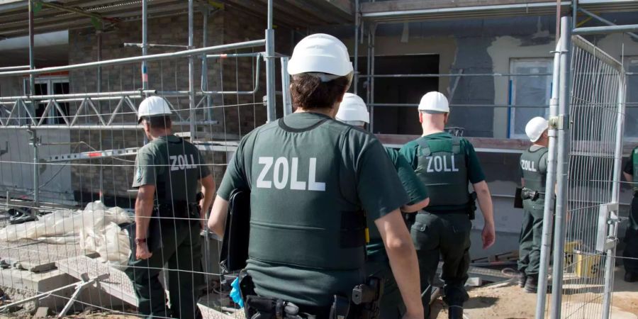 Zollbeamte betreten bei einer Razzia gegen Schwarzarbeit eine Baustelle.