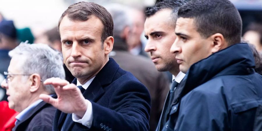 Frankreichs Präsident Emmanuel Macron (l.) winkt Bürgern zu, als er die Schäden der «Gelbwesten»-Proteste nahe der Champs-Élysées in Paris begutachtet.