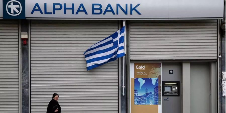 Eine Frau läuft an der Alpha Bank in Griechenland vorbei.