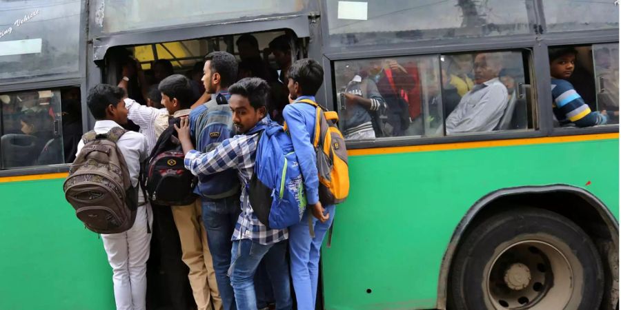 Indische Studenten halten sich an einem überfüllten Bus fest.