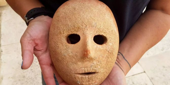 Eine 9000 Jahre alte Steinmaske wird präsentiert – die Maske hat Löcher für Augen und Mund sowie zur Befestigung an der Seite.