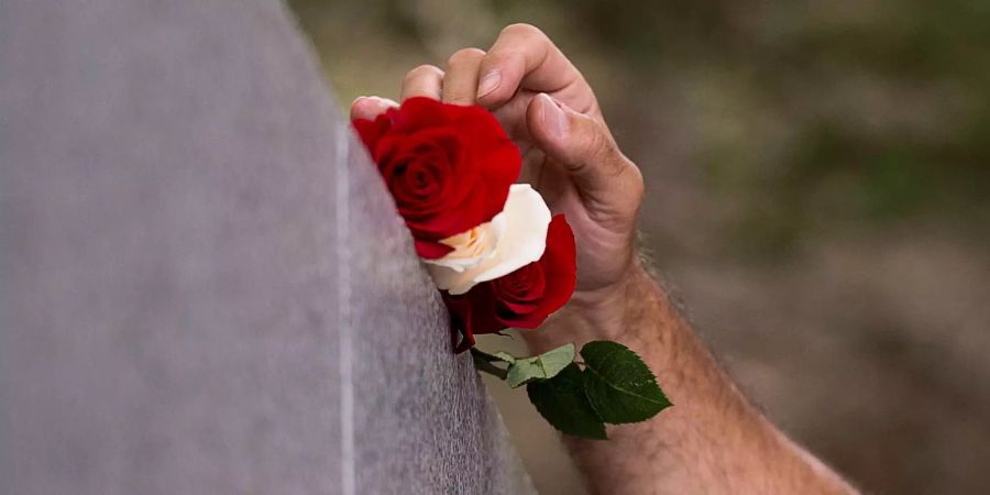 Ein Angehöriger legt Rosen auf das Monument am Bayswater Beach (CAN) im Andenken an seinen Vater.