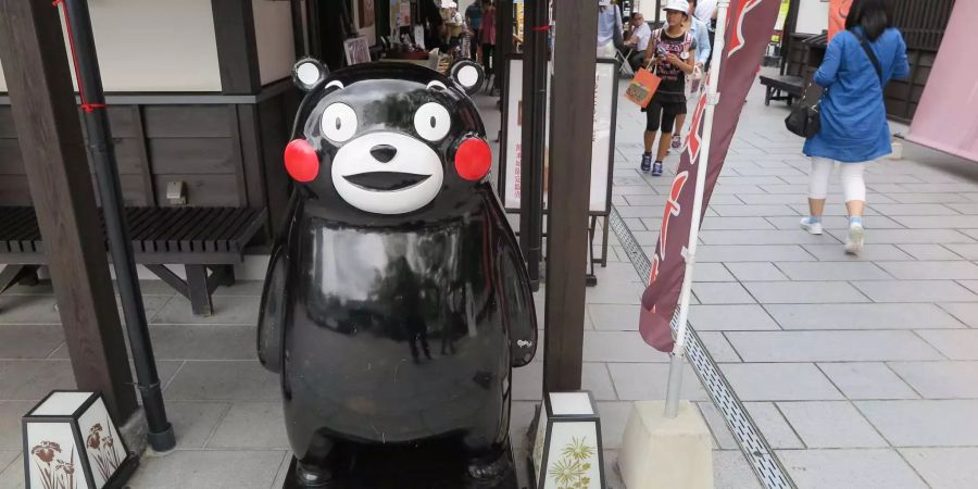 Kumamon, das Maskottchen der Provinz Kumamoto, steht an einer Hausecke.