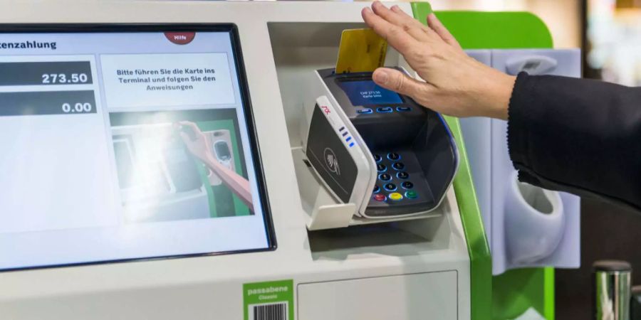 Ein Kunde zahlt mit einer Postcard an einem Self-Checkout-Automaten von Coop.