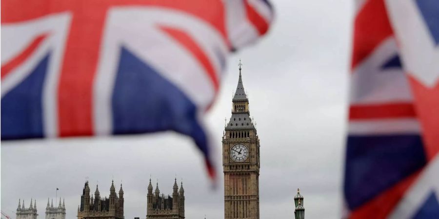 Britische Fähnchen an einem Touristen-Geschäft wehen vor den Houses of Parliament in London mit dem Elizabeth Tower (r), in dem die Glocke Big Ben hängt.