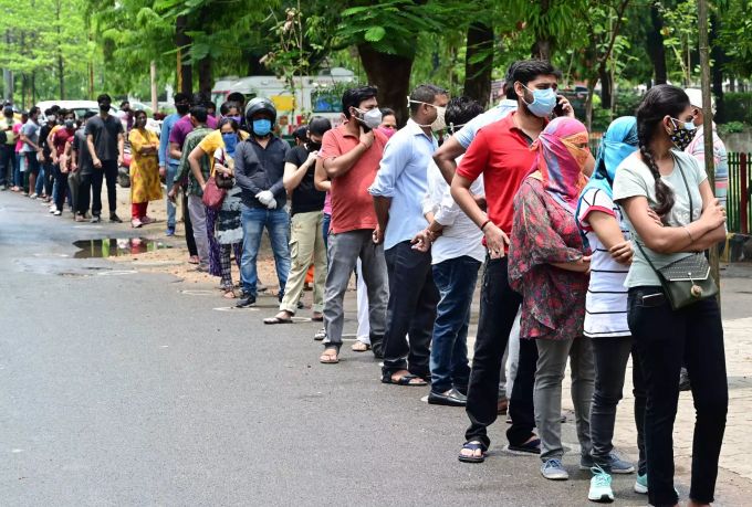 Menschen warten in einer langen Schlange, um sich im Moti Lal Nehru Medical College gegen das Coronavirus impfen zu lassen. Coronavirus - Indien