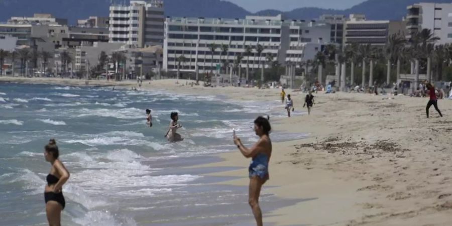 Menschen gehen am Strand von Arenal schwimmen. Foto: Clara Margais/dpa