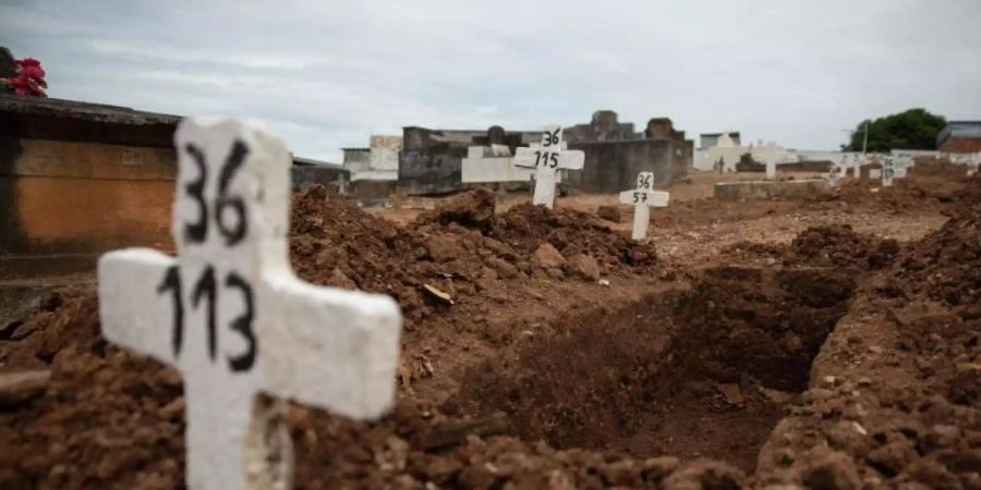 Ein einfaches Kreuz ohne Namen und mit einer Nummer steht an einem offenen Grab am Friedhof von Iraja in Rio de Janeiro. Foto: Fernando Souza/dpa