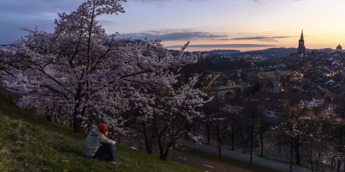 Zwei Personen genießen den Sonnenuntergang über der Stadt Bern während des Frühlings vom Rosengarten, Bern, Schweiz, Samstag, 3. April 2021. Bern Rosegarten
