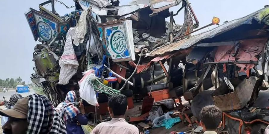 Anwohner betrachten das Wrack des Busses an der Unfallstelle in der Nähe von Dera Ghazi Khan. Foto: Saleem Khan/AP/dpa