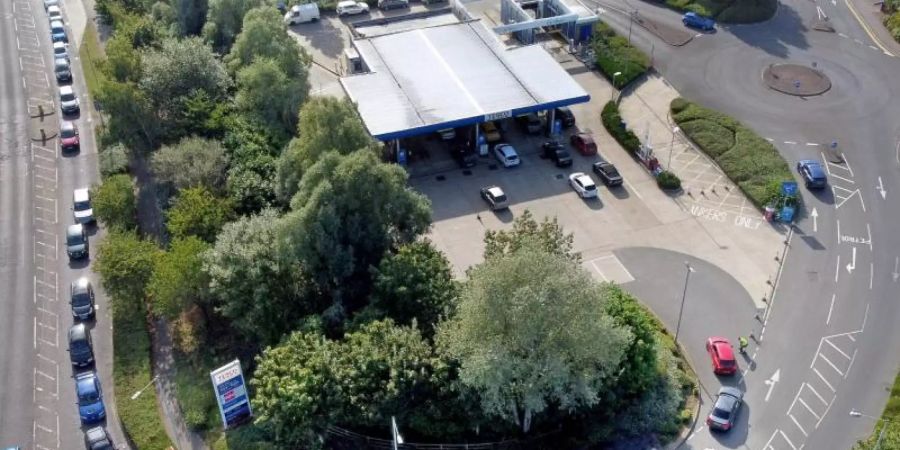 Autofahrer stehen mit ihren Fahrzeugen an einer Tankstelle in Ashford für Benzin in einer langen Warteschlange an. Foto: Gareth Fuller/PA Wire/dpa