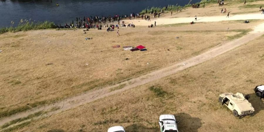 Offizielle Fahrzeuge der US-Grenzkontrolle stehen am Ufer des Flusses Rio Grande in der Nähe eines Lagers von Migranten, viele aus Haiti, nahe der Del Rio International Bridge. Foto: Julio Cortez/AP/dpa