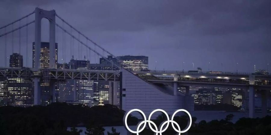 Die Olympischen Ringe in der Abenddämmerung Tokios. Foto: Felipe Dana/AP/dpa