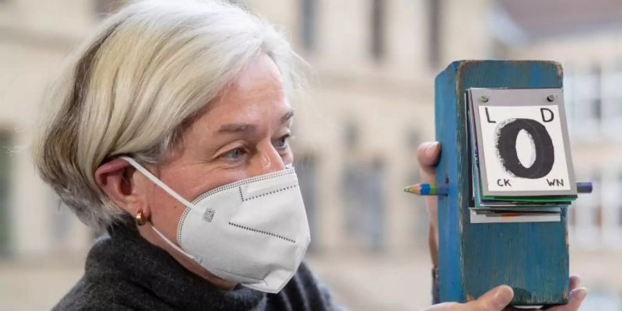 Martina Dannert, Bibliotheksleiterin der Stadtbibliothek Osnabrück, hält einen Holzblock mit der Aufschrift «Lockdown» in den Händen. Ihr Projekt thematisiert die Folgen des Lockdowns und macht die Bürger selber zu Künstlern. Foto: Friso Gentsch/dpa