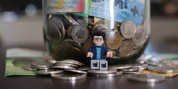 Eine Rechtsschutzversicherung schützt vor finanziellen Folgen bei Rechtsstreitigkeiten. Legomännchen vor Geldglas.