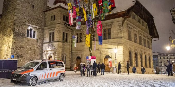 Menschen stehen am frühen Morgen in der Altstadt auf dem Rathausplatz um den Guggenbaum am sogenannten «Schmutzigen Donnerstag», dem Beginn der Fastnacht, davor hält ein Polizeiwagen. Coronavirus - Fasnacht in Luzern