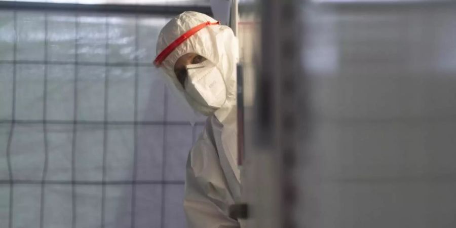 Ein Helfer der Johanniter wartet in einem Corona-Testzentrum an einem Flughafen auf den nächsten Patienten. Foto: Julian Stratenschulte/dpa