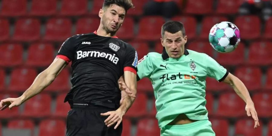 Lucas Alario (l) kämpft mit Mönchengladbachs Verteidiger Stefan Lainer um den Ball. Foto: Ina Fassbender/AFP POOL/dpa