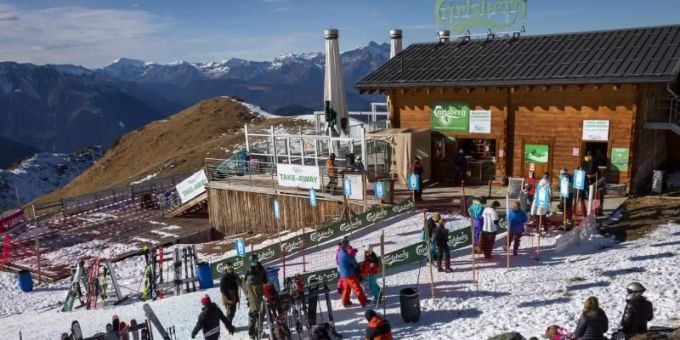 Skifahrer stehen auf einer Piste im Walliser Skigebiet vor einem Restaurant Schlange (Archivbild vom 28.11.2020). Foto: Jean-Christophe Bott/KEYSTONE/dpa Skigebiet Saison