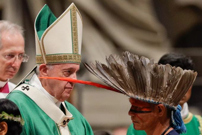 Ein Mitglied eines indigenen Volkes mit bemaltem Gesicht und Federschmuck am Kopf trifft auf Papst Franziskus während der Eröffnungsmesse für die Amazonas-Synode. Der Papst appellierte an die Bischöfe sich für den Amazonas und seine indigenen Völker einzusetzen. Amazonas-Synode im Vatikan