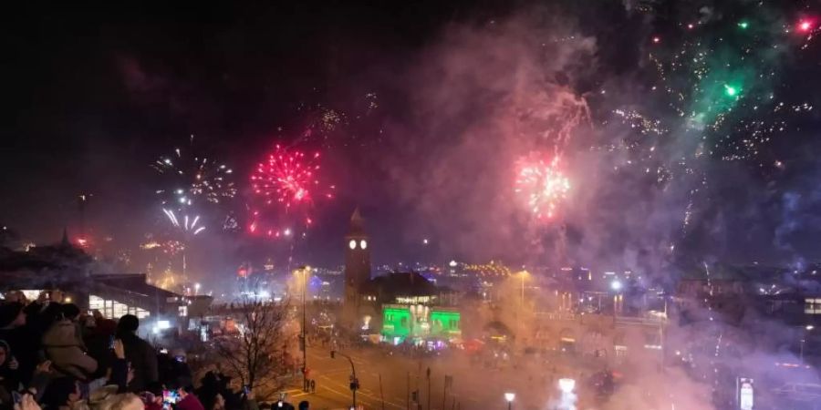 Hunderte Schaulustige beobachten das Feuerwerk an den Hamburger Landungsbrücken. Foto: Jonas Walzberg/dpa