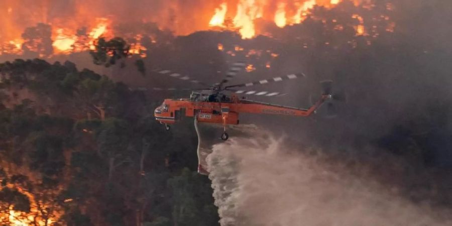 Ein Löschhubschrauber fliegt über ein Buschfeuer in der Nähe von Bairnsdale in der Region East Gippsland Shire im Bundesstaat Victoria. Foto: ---/STATE GOVERNMENT OF VICTORIA/AAP/dpa